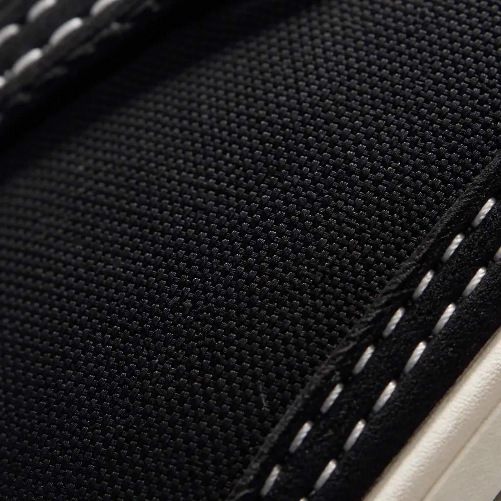 Extreme close-up macro photograph of the black woven textile upper texture showing intricate weave pattern and premium material quality