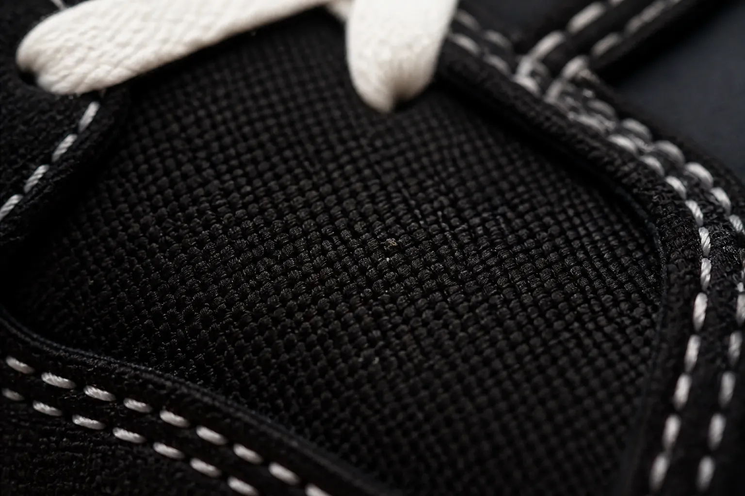 Close-up macro shot of the premium black woven textile upper with intricate crosshatch pattern detail