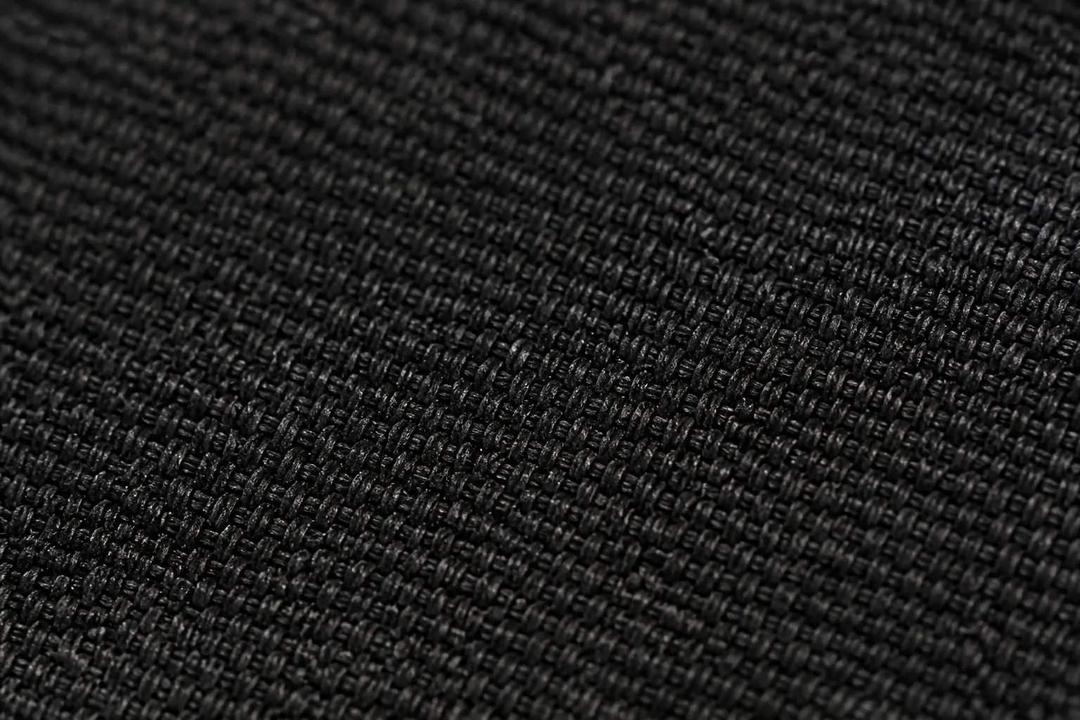 Extreme close-up macro photograph of the black woven textile upper texture showing the intricate interlocking weave pattern, subtle sheen, and premium material quality that sets this sneaker apart