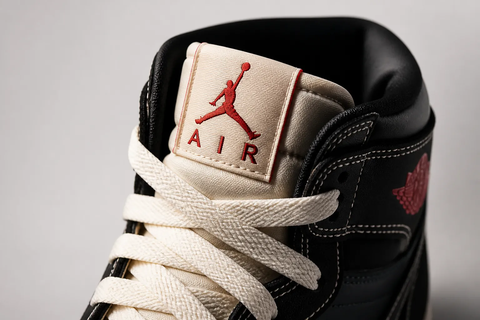 Professional product shot of the iconic Jumpman logo embroidered on the Air Jordan 1 tongue, displayed with dramatic lighting that emphasizes the premium stitching and the legendary heritage symbolized by Michael Jordan's silhouette