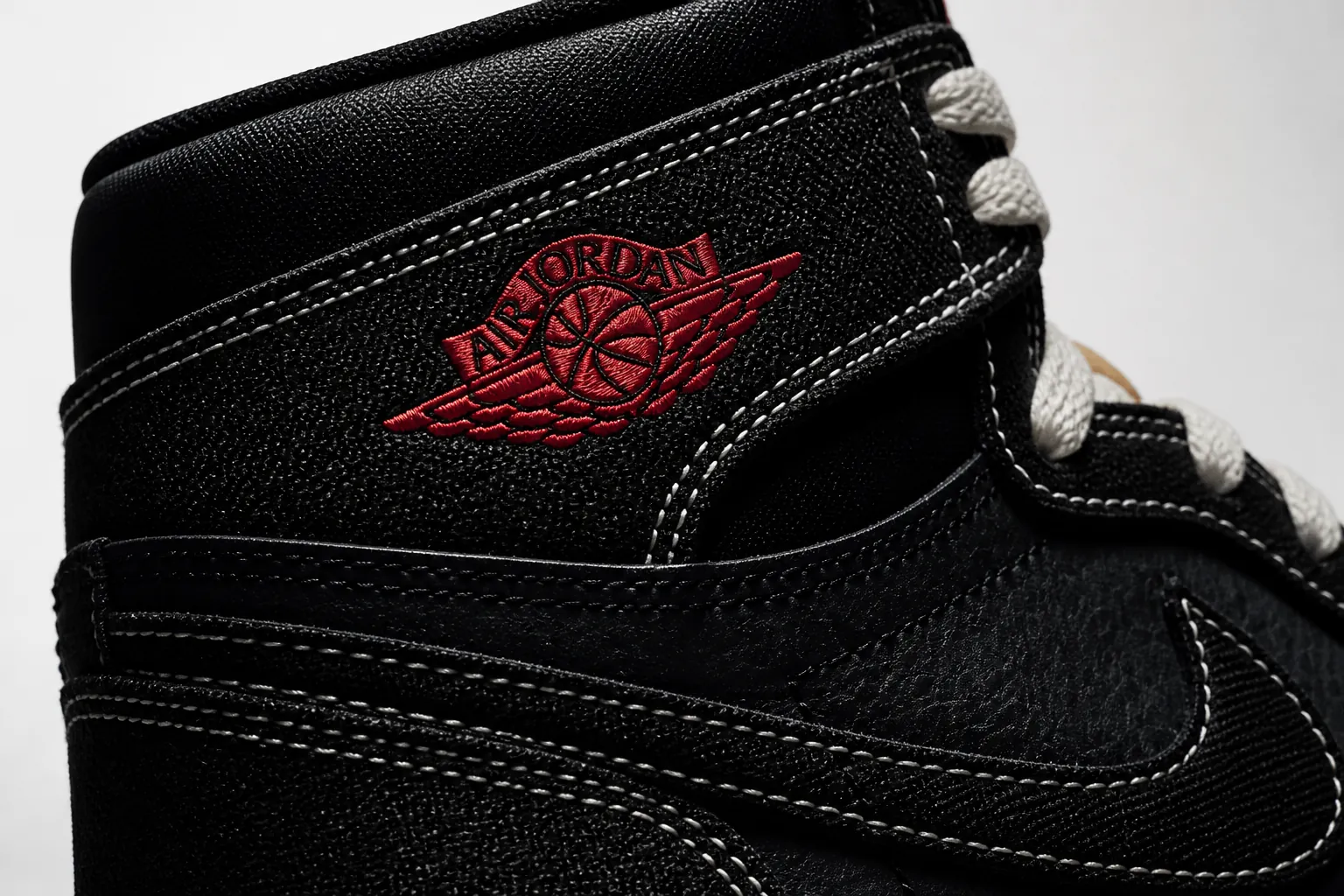 Close-up macro shot of the Air Jordan 1 Flight Club woven black textile upper with intricate texture patterns, dramatic moody lighting highlighting the premium construction and Jumpman logo embroidery