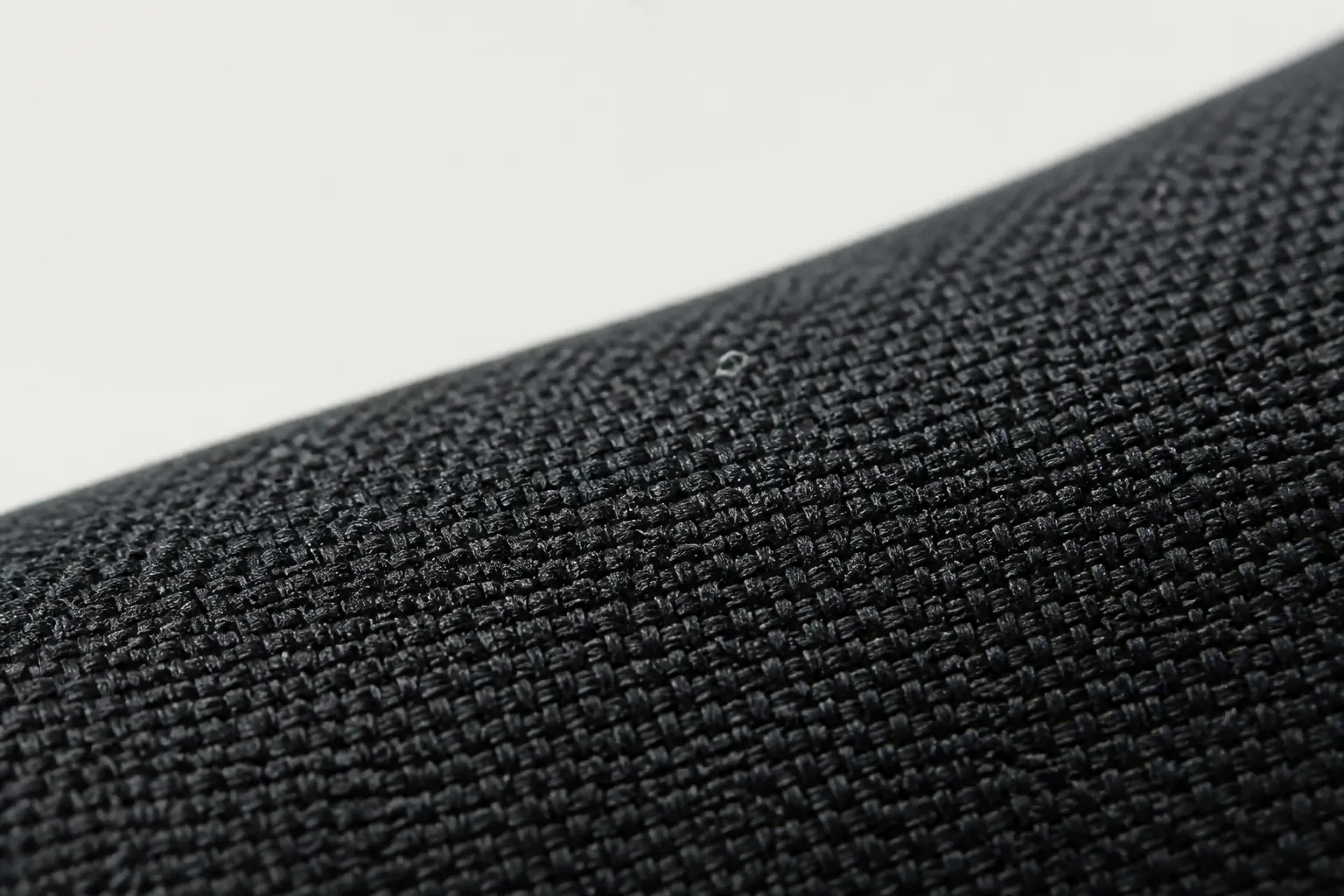 Close-up macro shot of black woven textile upper showing intricate crosshatch pattern with subtle texture variations and premium material quality