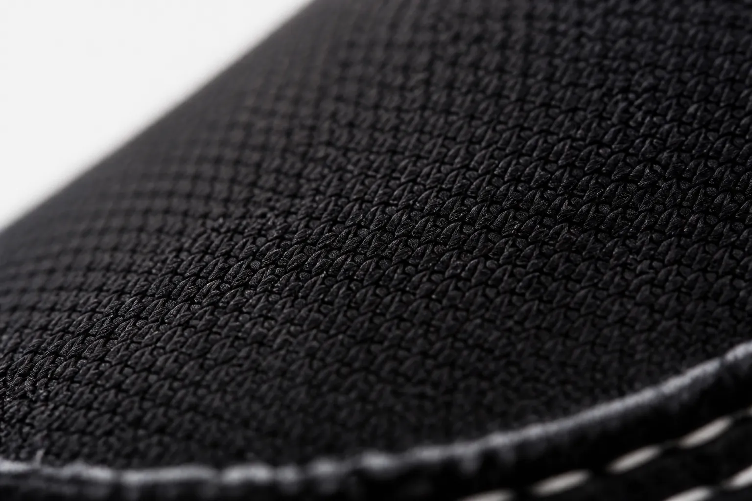Close-up macro shot of the black woven textile upper texture showing intricate crosshatch pattern with visible depth and premium material quality under studio lighting