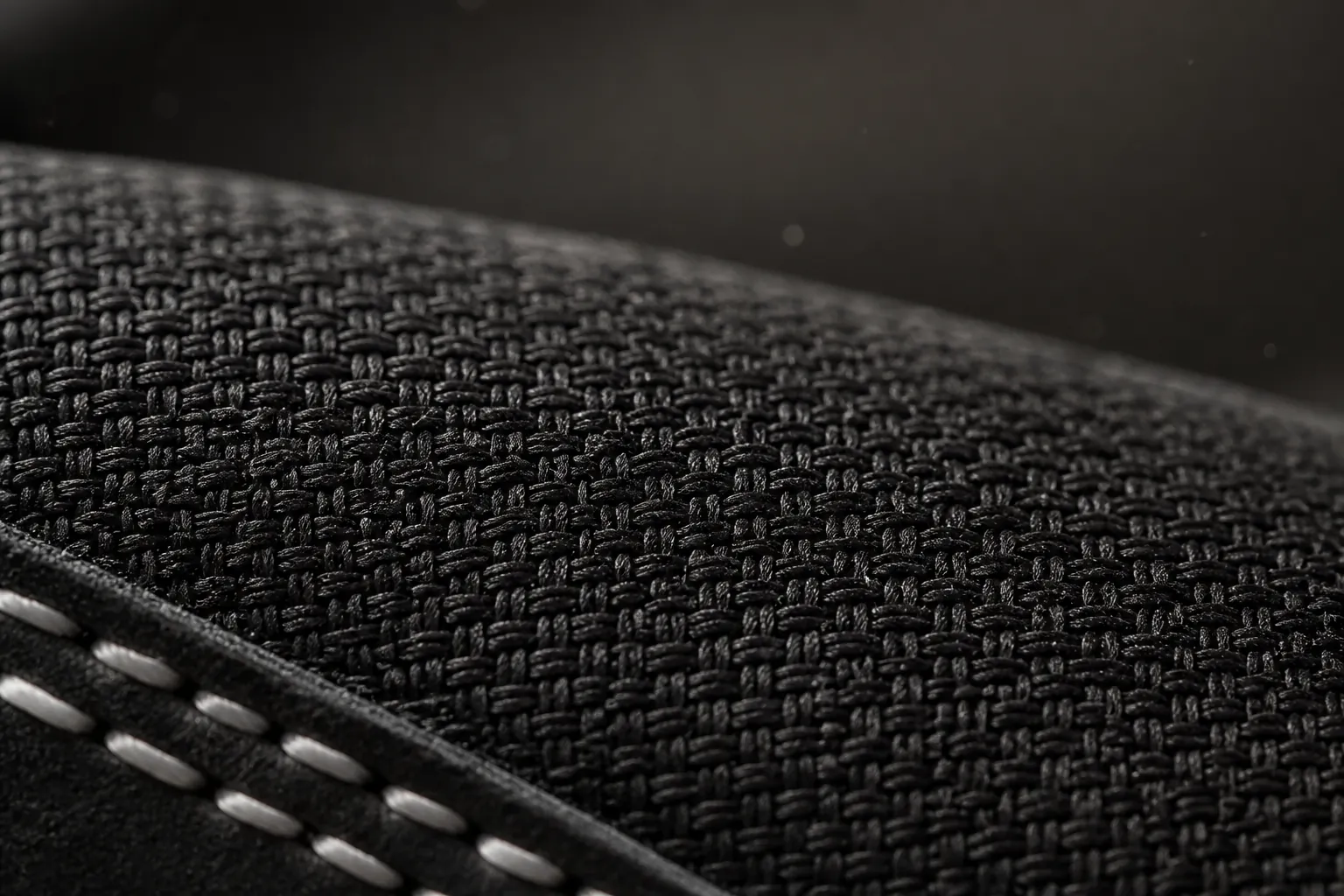 Extreme close-up macro shot of the premium black woven textile upper showing intricate crosshatch weaving pattern and durability